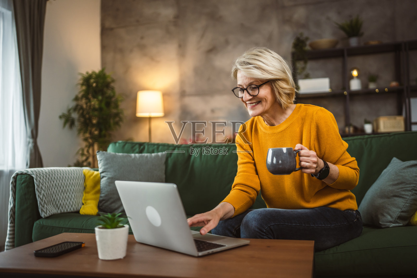 成熟的金发白人女性在家里使用笔记本电脑工作照片摄影图片