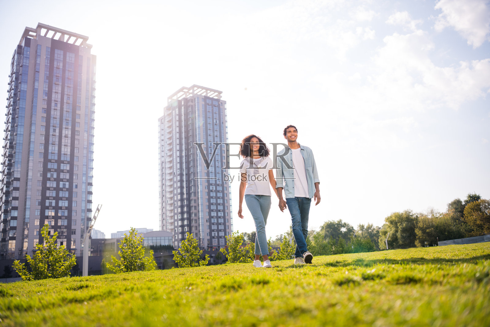 两个宁静田园的人挽着手走在绿色的草地温暖的阳光明媚的天气城市中心公园户外照片摄影图片