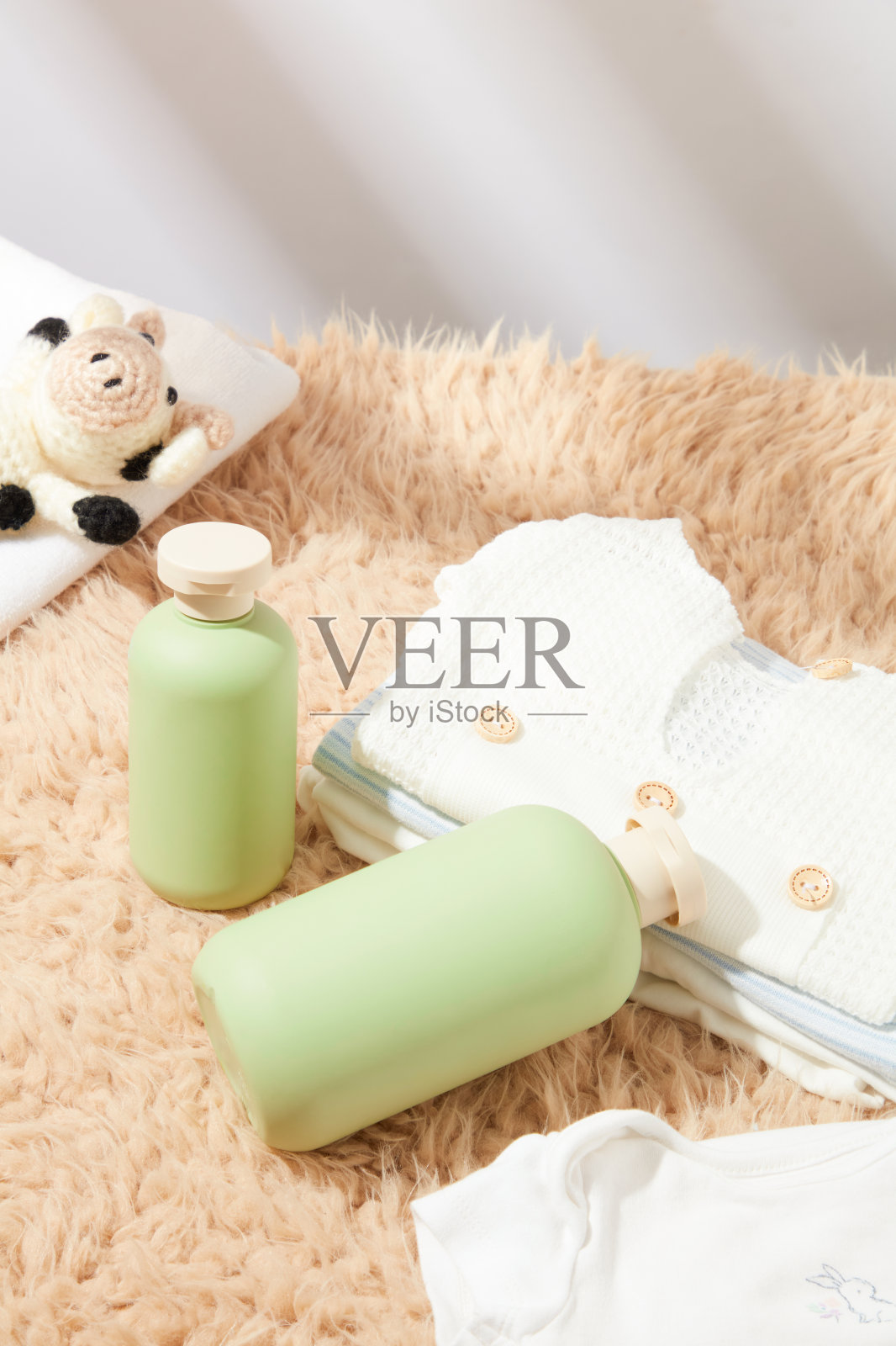 一些衣服平躺在棕色的地毯上,旁边是没有标签的绿色瓶子,俯视图。空白文字和婴儿卫生用品广告照片摄影图片