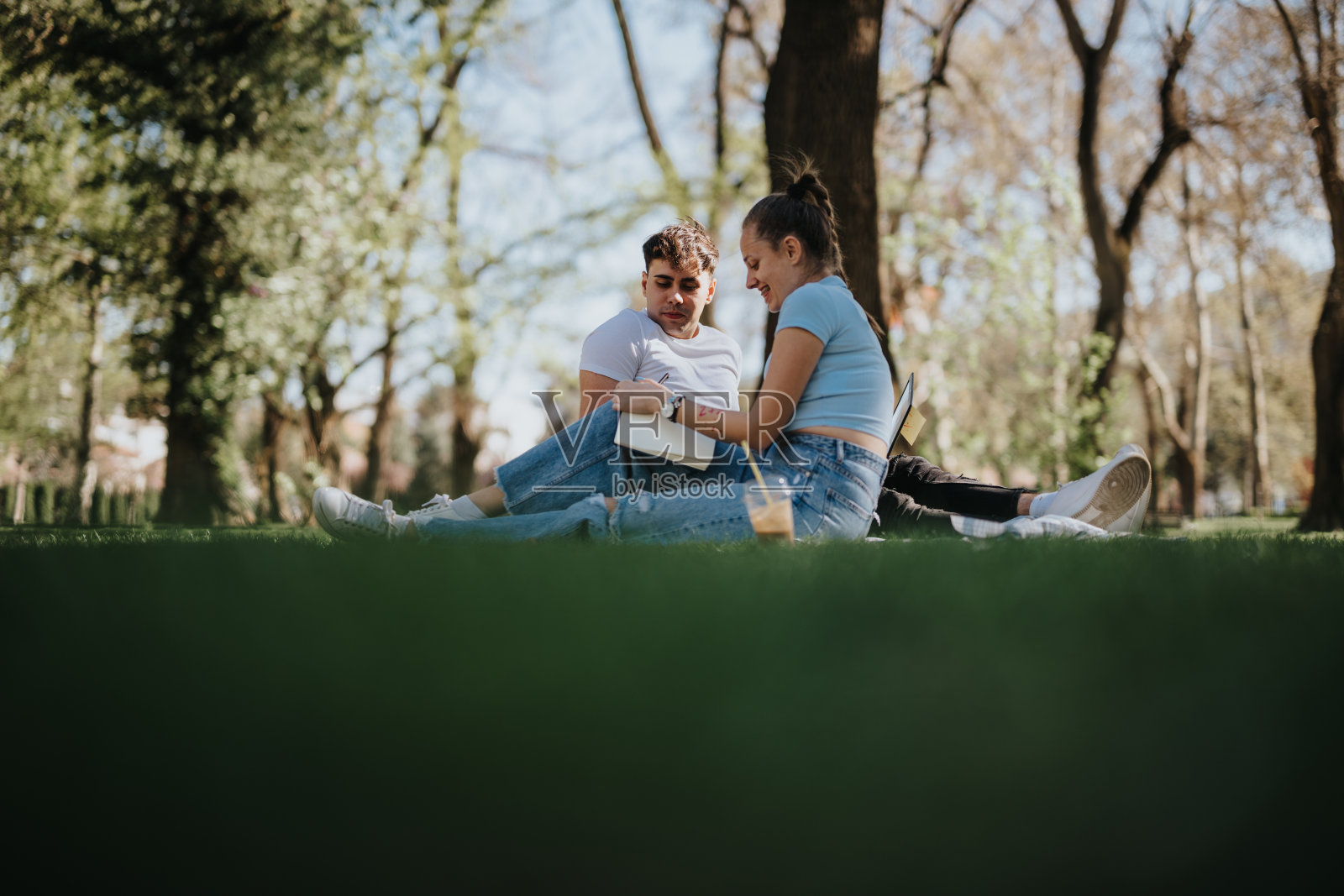 高中情侣一起在公园里看书照片摄影图片