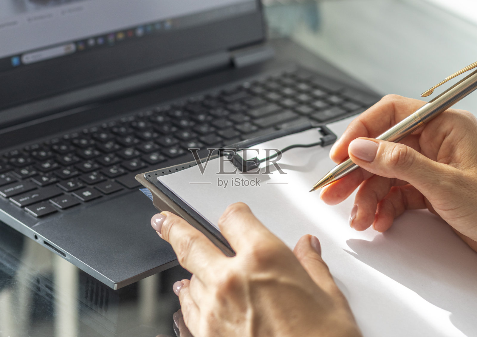 穿着商务服装的女人在办公室里用笔记本电脑做笔记的特写镜头照片摄影图片