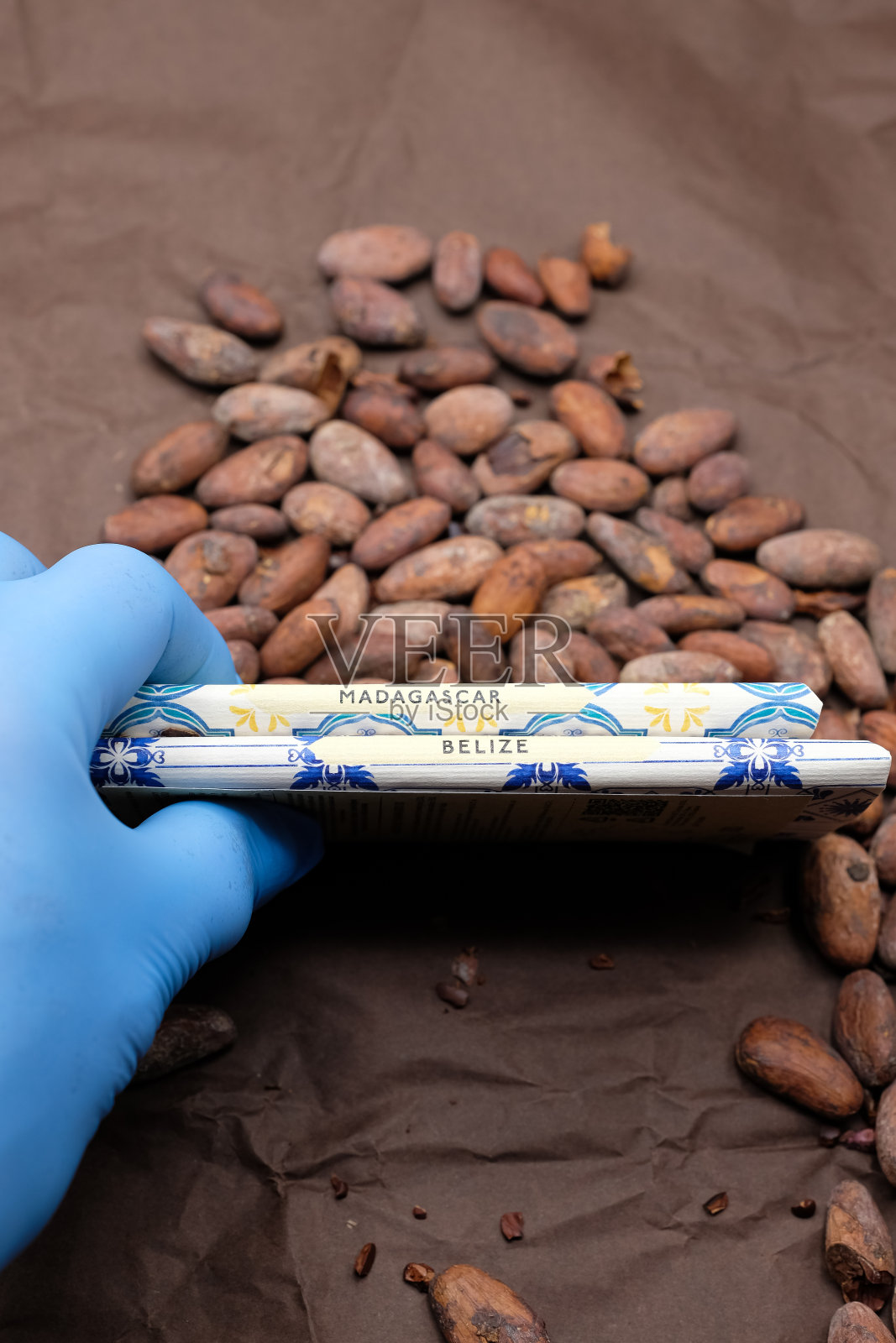 马达加斯加和伯利兹的风土巧克力棒。手戴着一次性手套。可可豆。照片摄影图片
