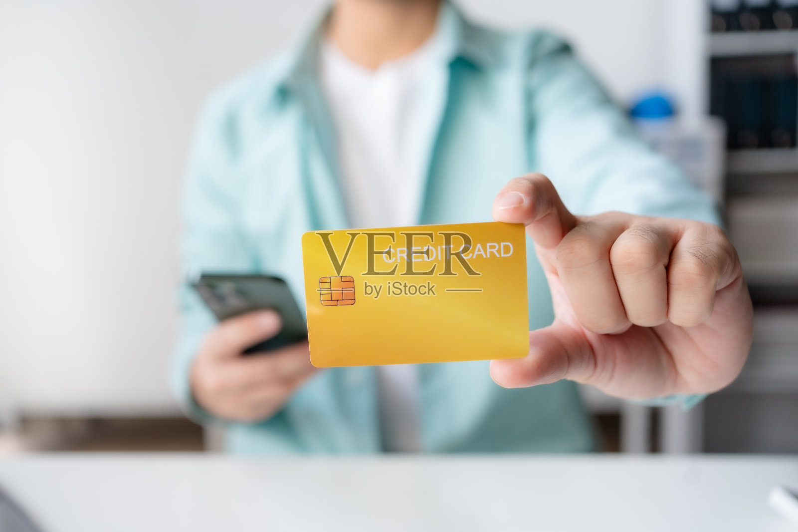 男子使用信用卡和智能手机进行金融交易。年轻人在网上支付,使用银行服务,输入信息,购物,在网上商店订购,做安全支付。照片摄影图片