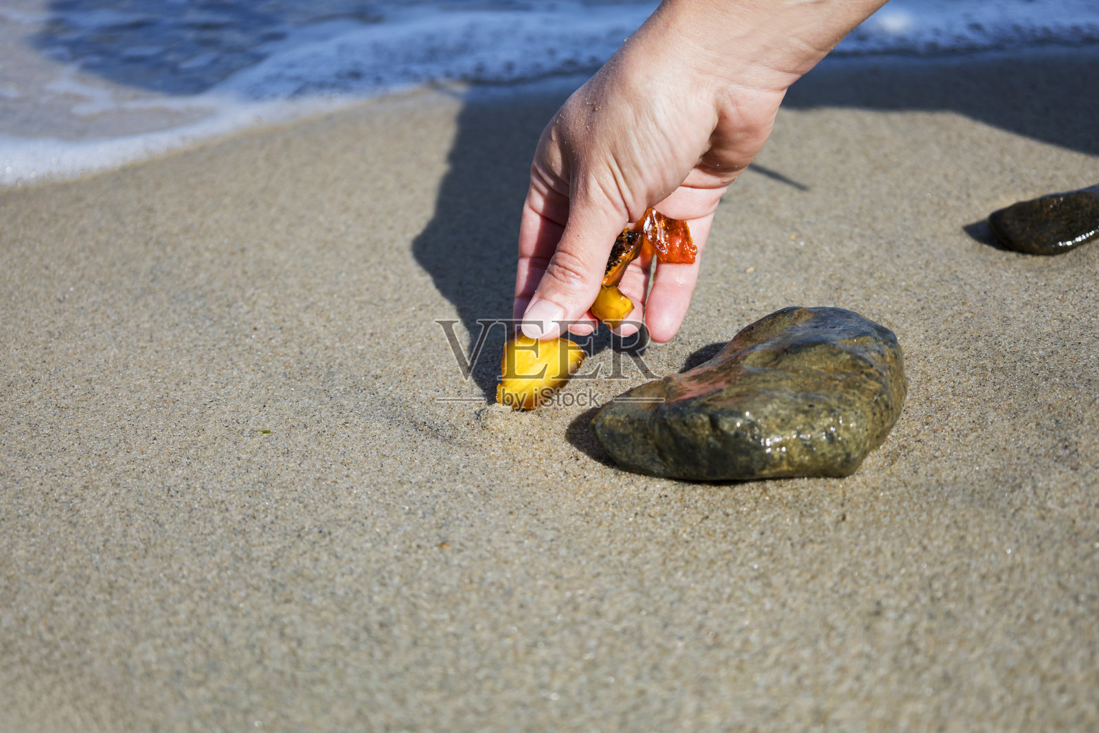 一块块美丽的琥珀在大海的手背景下。在你的手掌里有一块发光的琥珀。日长石。照片摄影图片