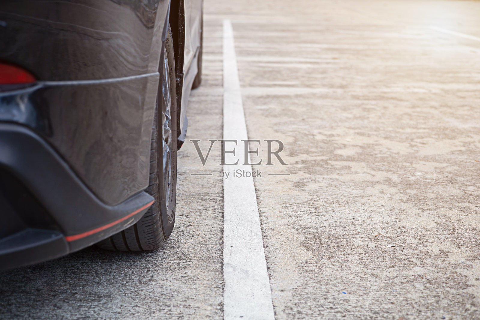 在混凝土路面上,平行于白色交通线停放的车轮。照片摄影图片