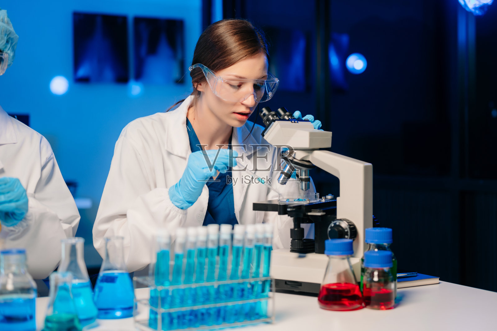 年轻的科学家在医学实验室里进行研究调查,一位研究人员在实验室里使用显微镜照片摄影图片