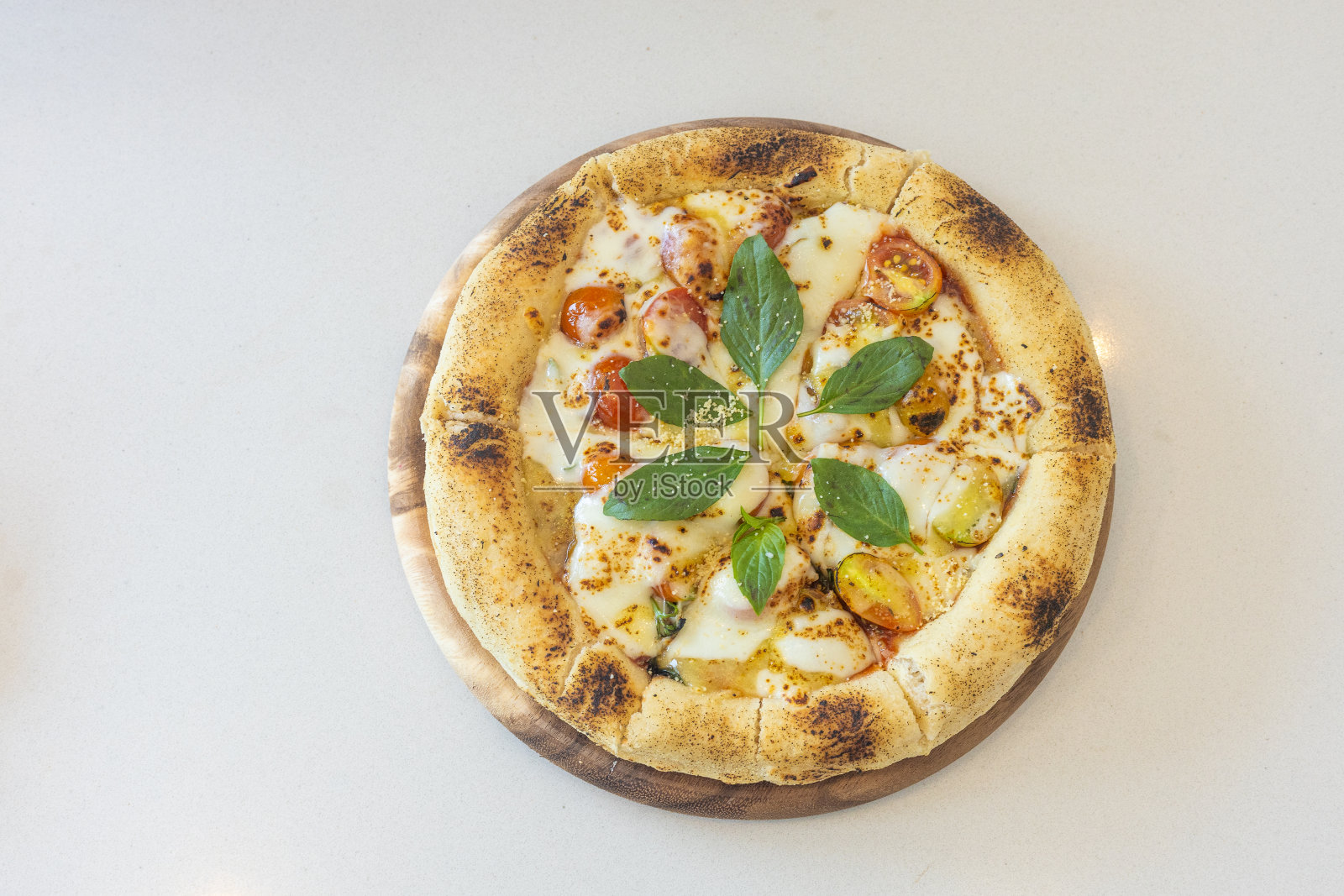 披萨上面有一片绿叶。比萨在一块木板上。披萨上面有奶酪和西红柿照片摄影图片