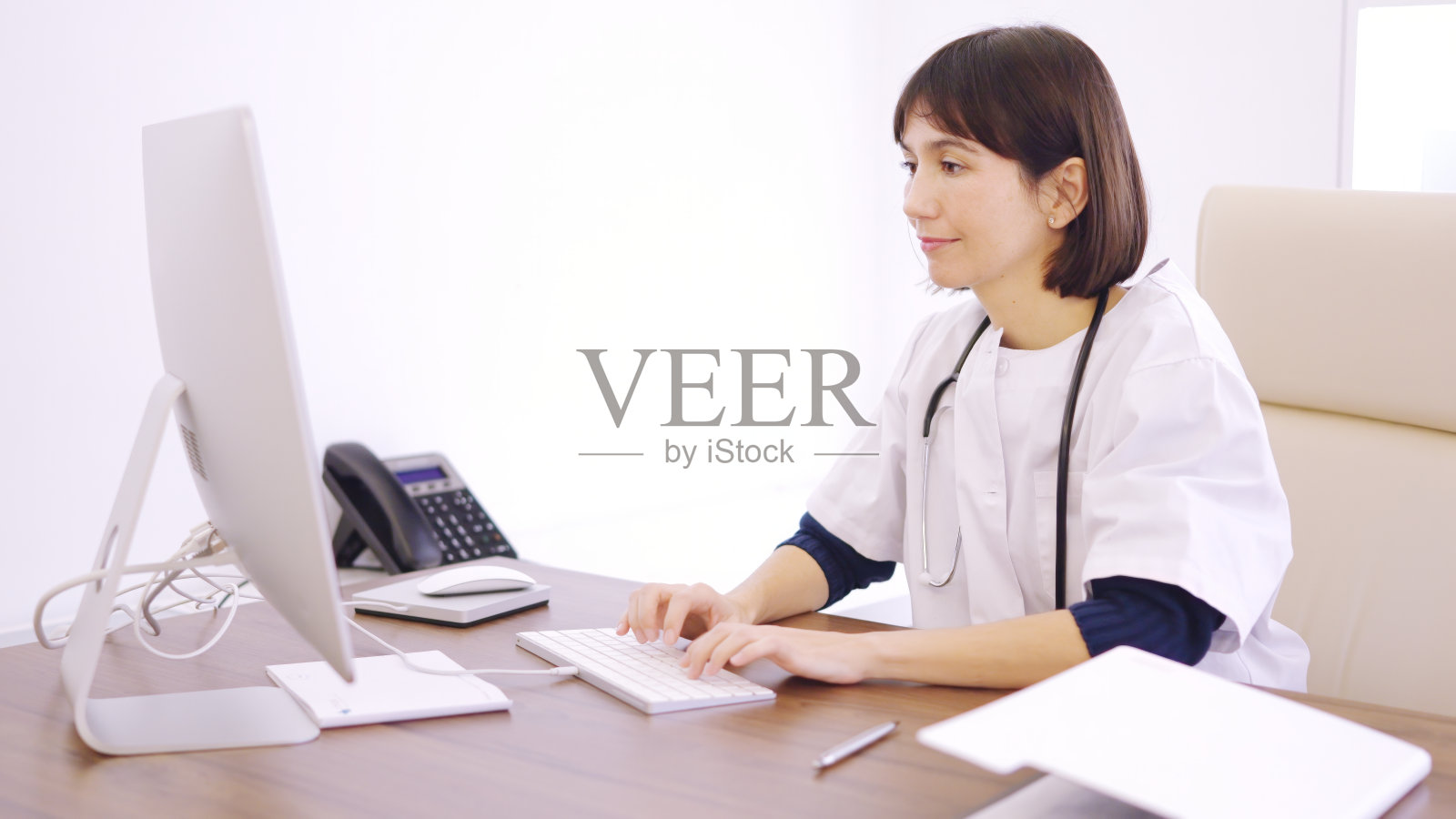 医生坐在诊所的桌子上使用电脑照片摄影图片