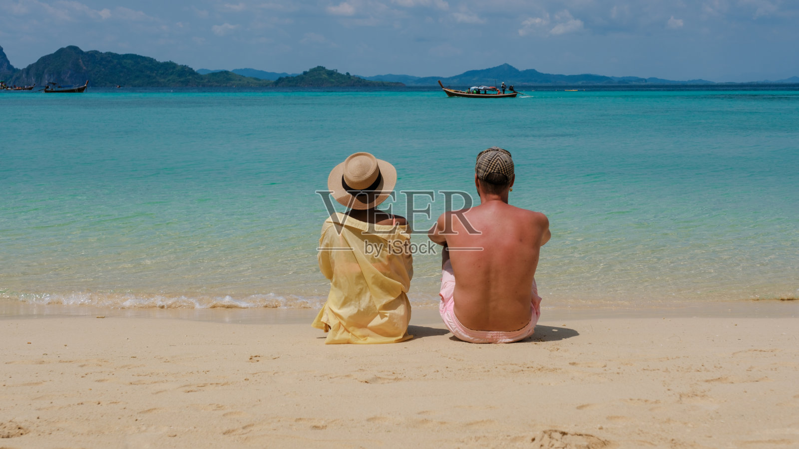 坐在泰国克拉丹岛海滩上的一对男女的臀部照片摄影图片