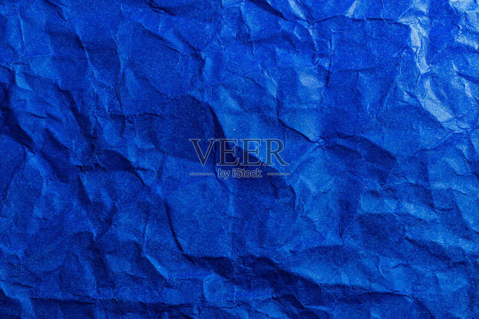 蓝纸纹理背景。皱巴巴的蓝色纸抽象形状背景。照片摄影图片