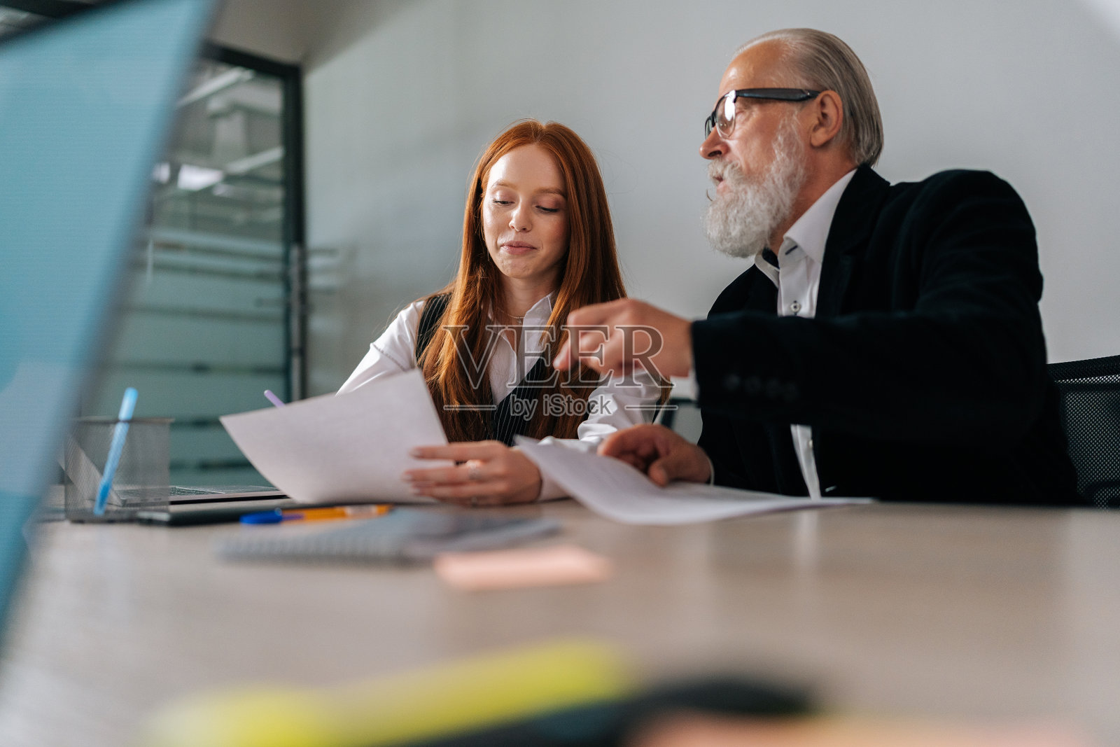 低视角熟练成熟的男性ceo执行经理主管穿着正装指导微笑的年轻女实习生,帮助指导实习生。照片摄影图片
