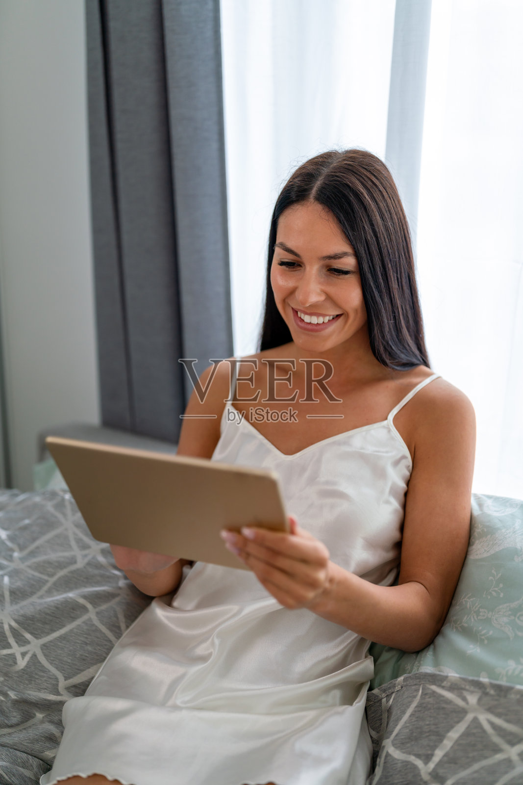 快乐的美女在家里用平板电脑看视频或享受娱乐内容照片摄影图片