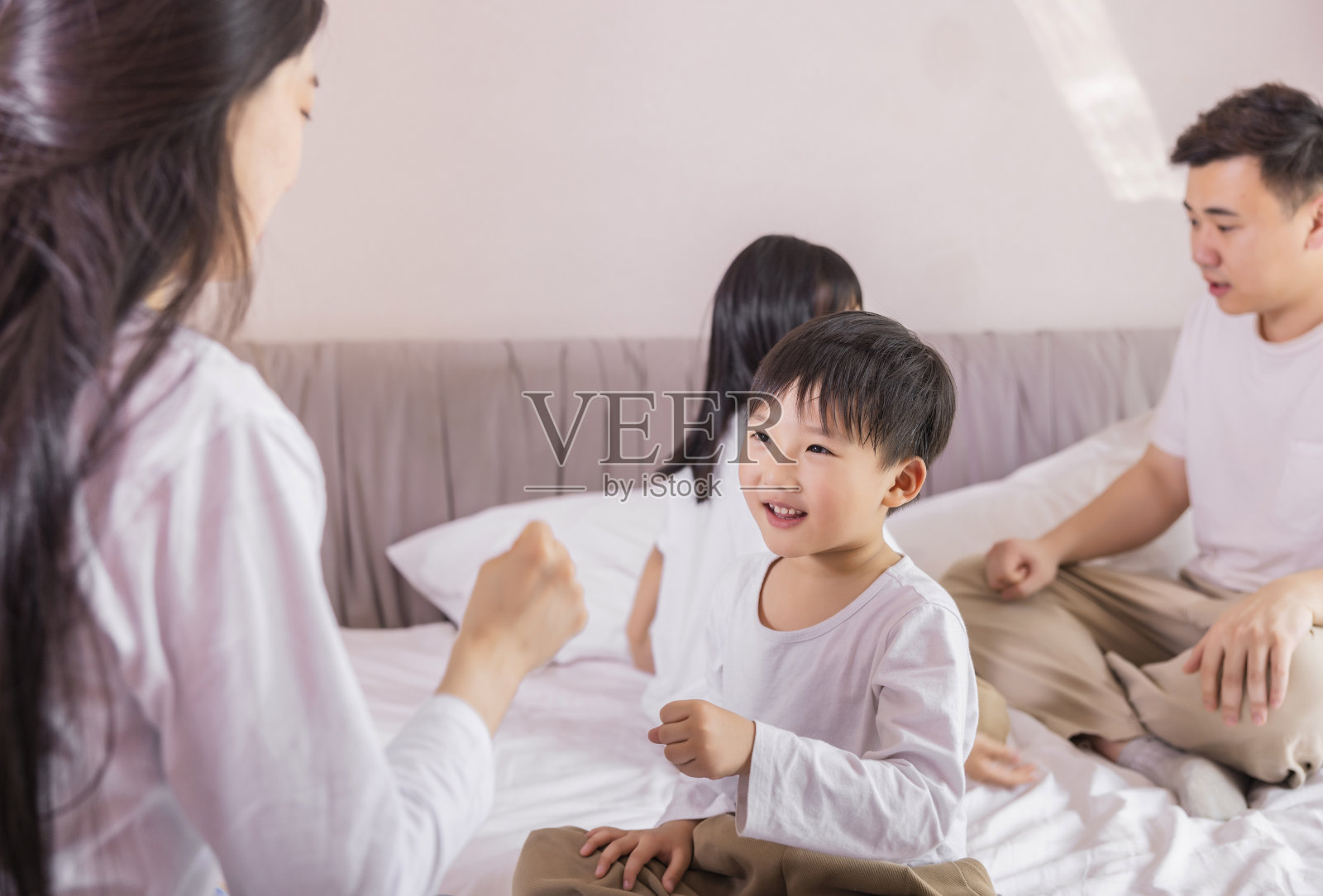 一家四口坐在床上玩游戏照片摄影图片