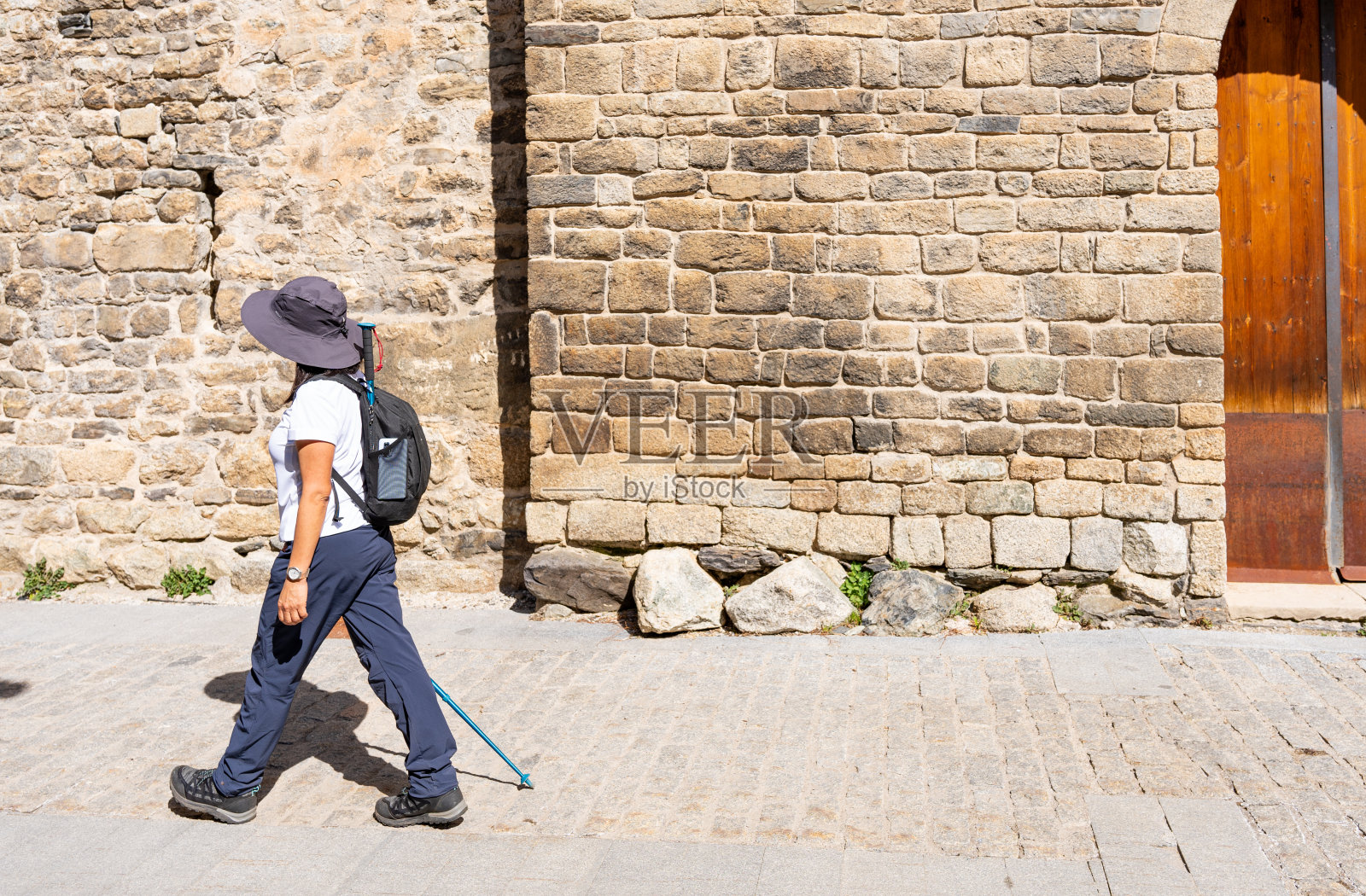 无法辨认的女性徒步旅行者穿过一个小山村,她徒步穿越了加泰罗尼亚的比利牛斯山脉照片摄影图片