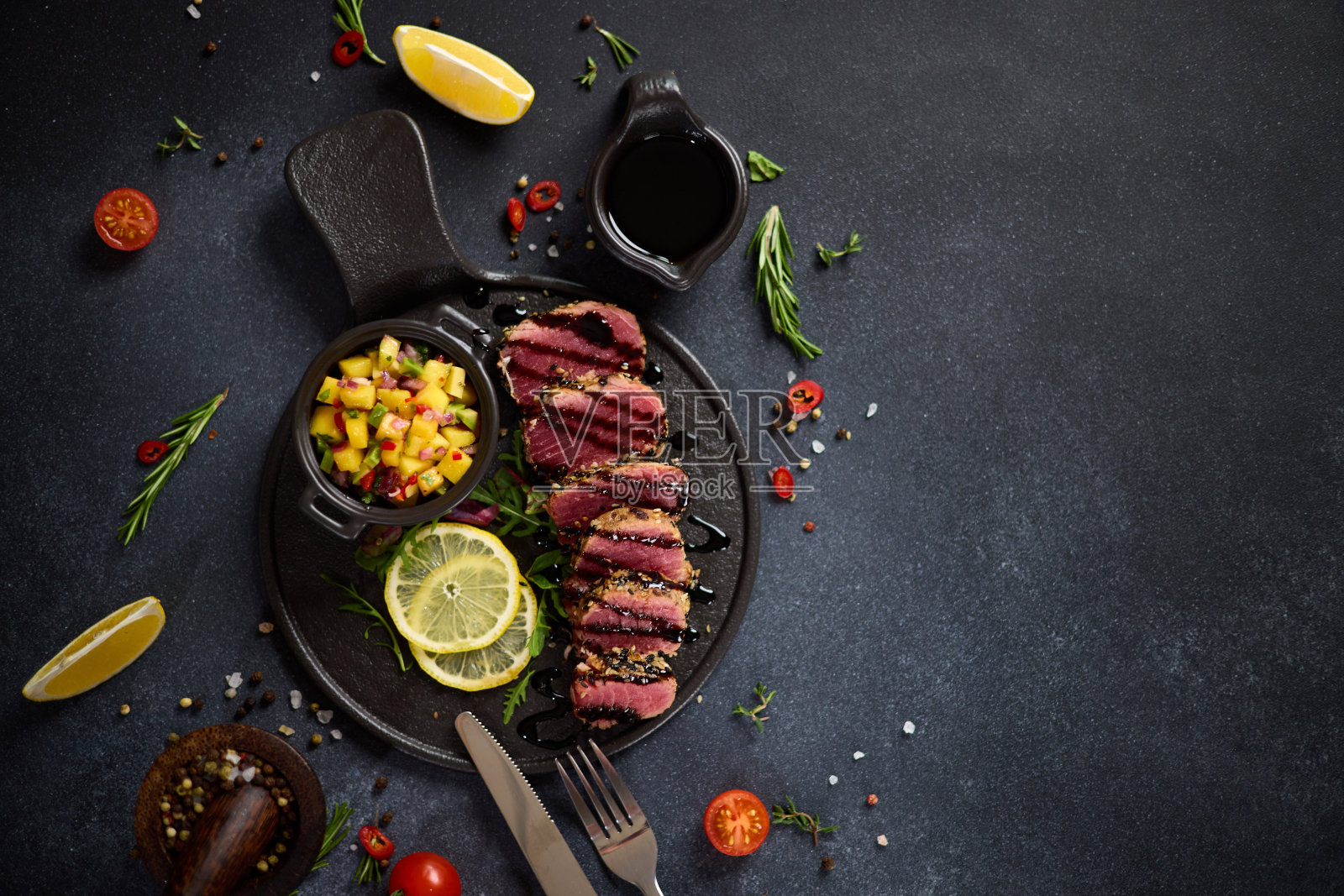 切片有机烤金枪鱼片覆盖芝麻和芒果莎莎在黑色陶瓷服务板照片摄影图片