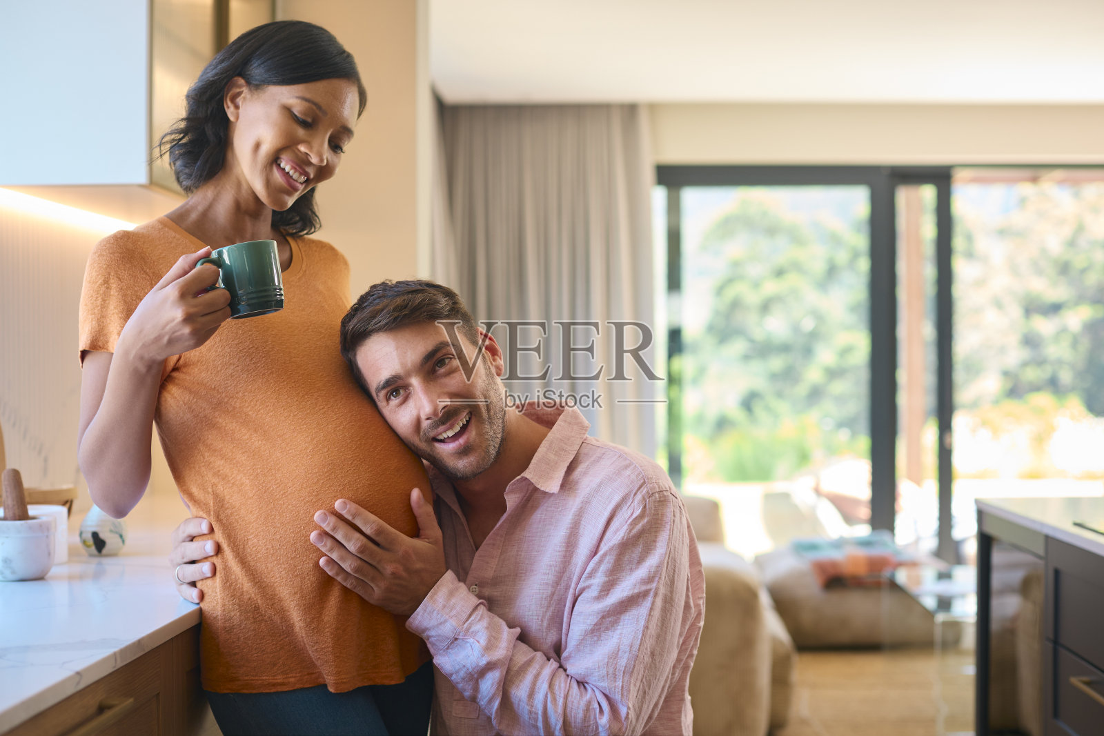 有爱的多种族夫妇,怀孕的女人和男人在家听婴儿的心跳照片摄影图片