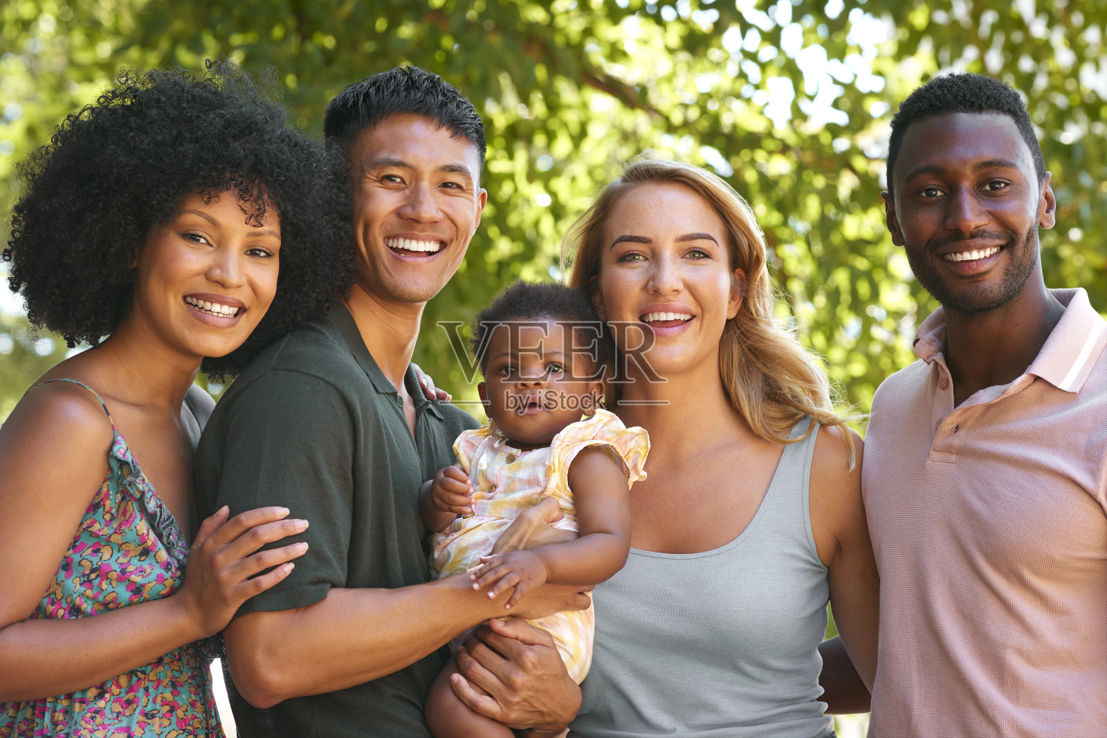 多种族家庭和朋友在野外集体拥抱婴儿的肖像照片摄影图片