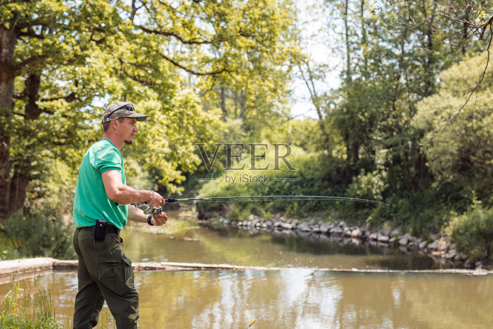 渔夫在河边钓鱼,周围是美丽的大自然照片摄影图片