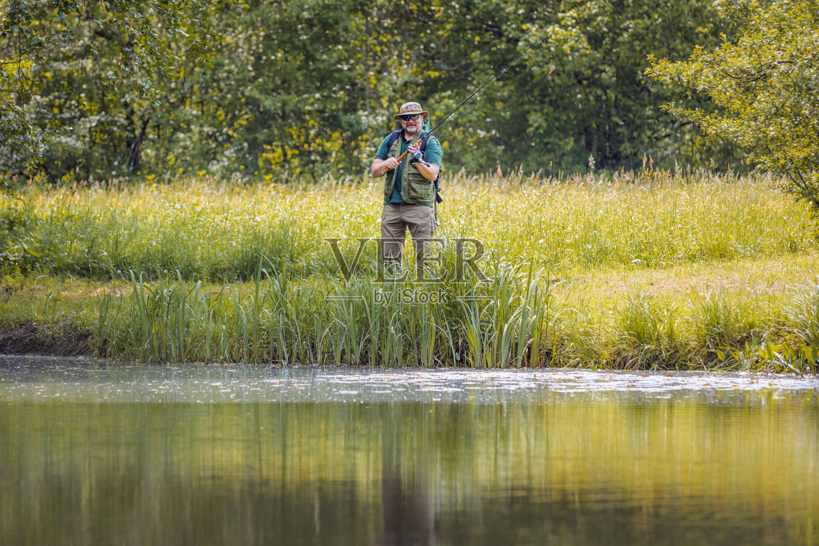 淡水渔夫拿着带纺线的鱼竿照片摄影图片