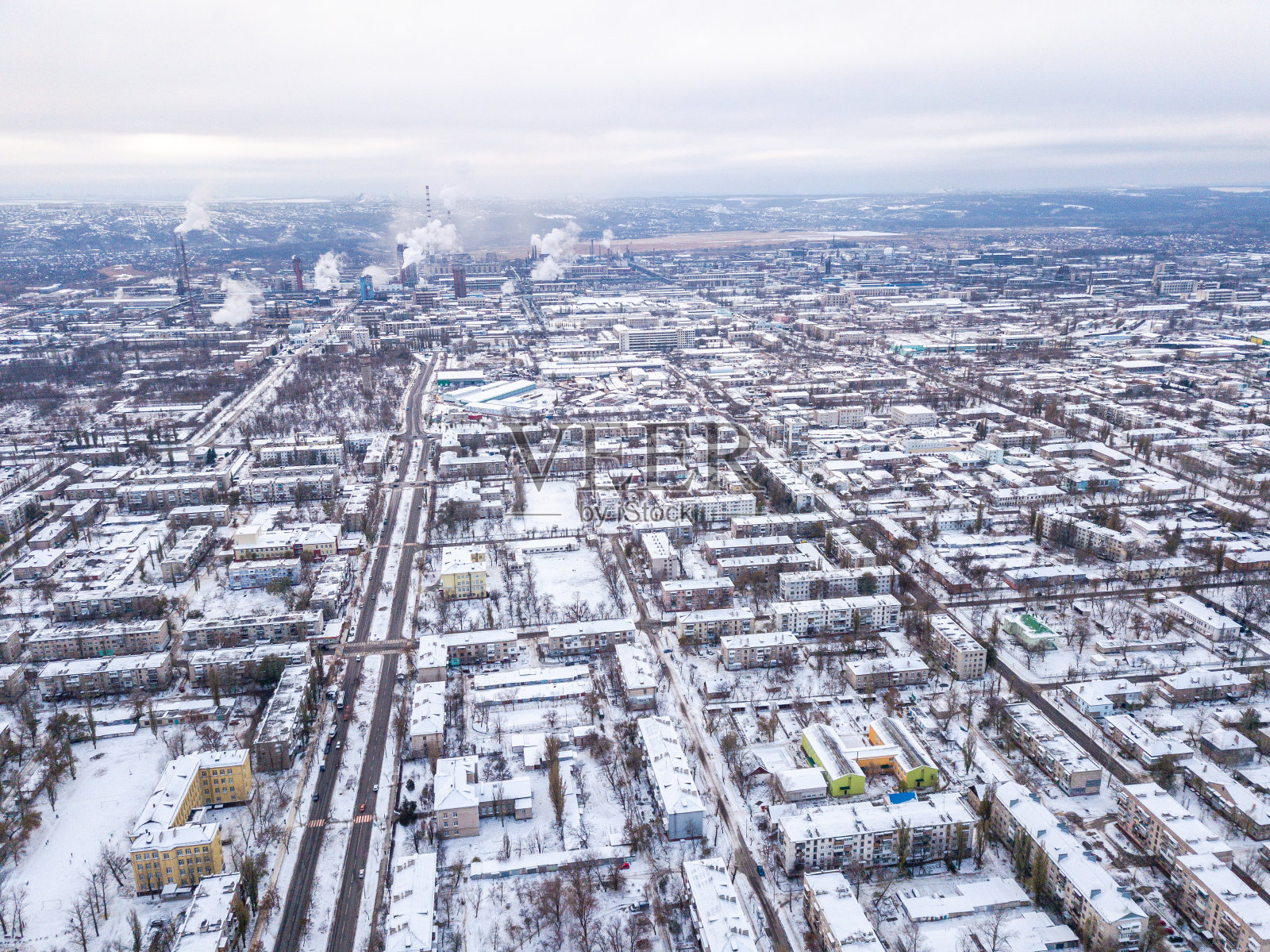 从无人机上俯瞰城市道路和被雪覆盖的房屋。照片摄影图片