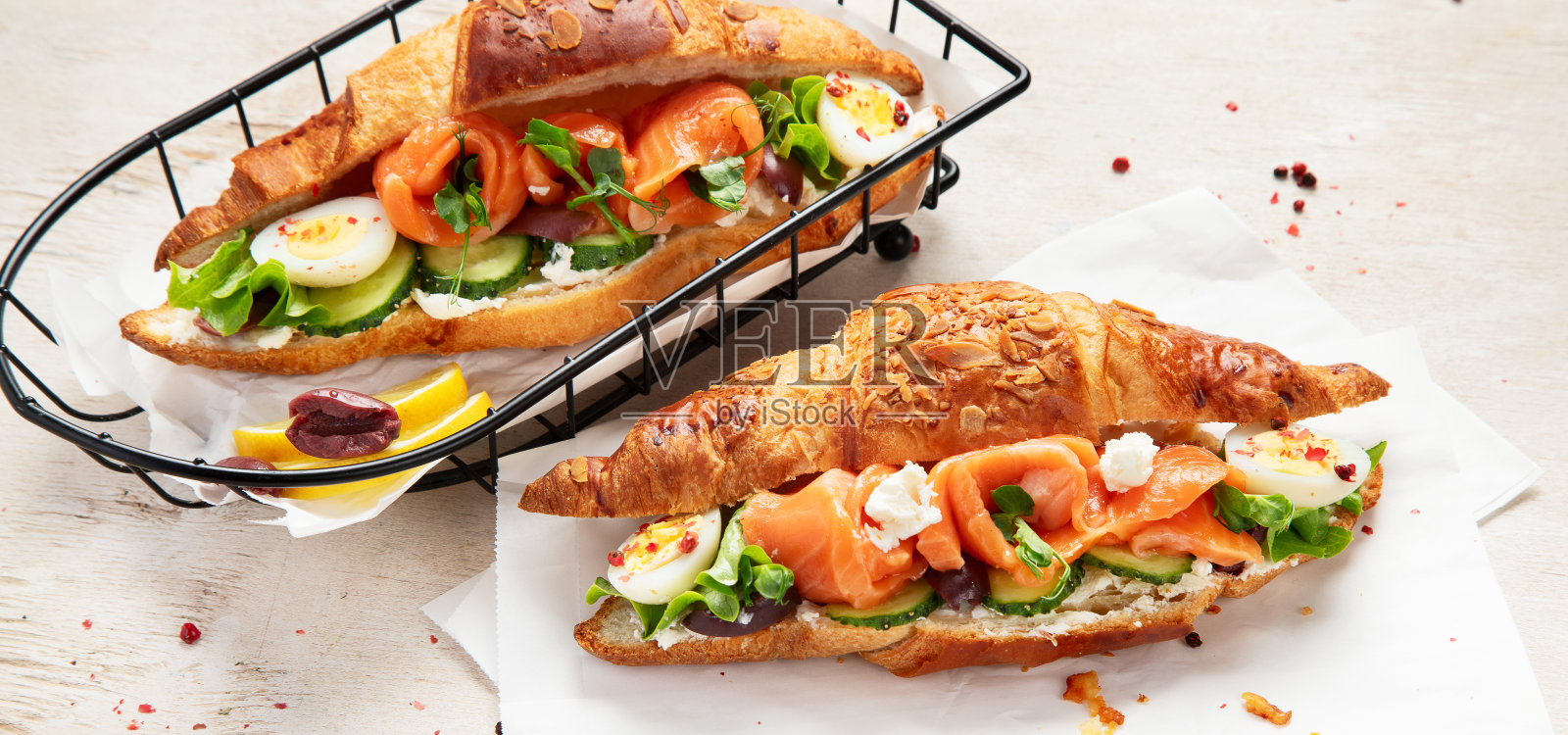 清淡的盐腌健康早餐。新鲜鲑鱼牛角包配奶油芝士、黄瓜、鸡蛋及沙拉照片摄影图片