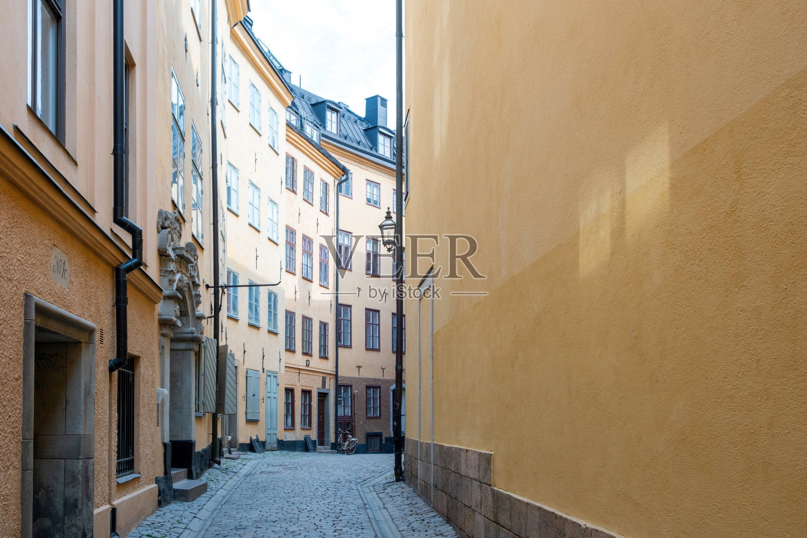 瑞典斯德哥尔摩。在Gamla Stan老城区,狭窄的铺砌小巷,带有外部排水沟的建筑。照片摄影图片