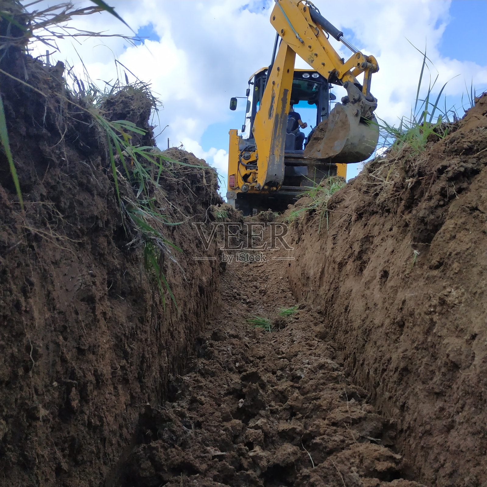 在挖好的沟渠上布线电缆,为地面上的房屋供电。照片摄影图片