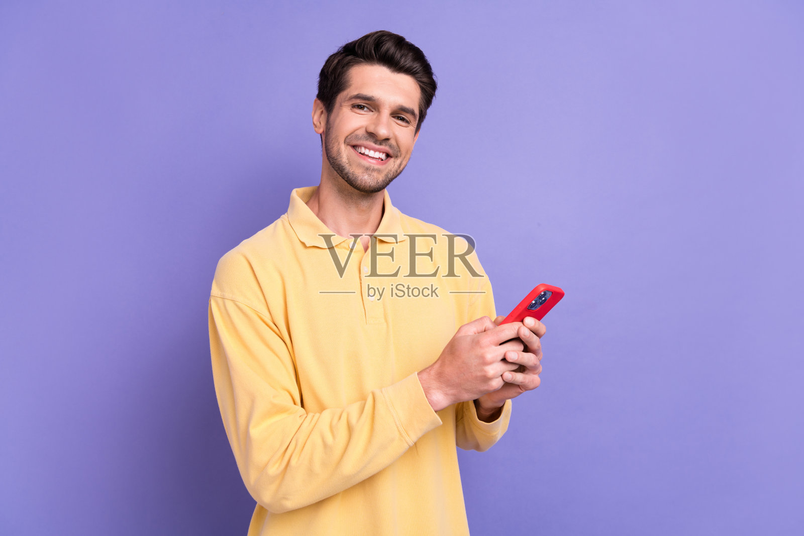 迷人的积极的家伙穿黄色衬衫的照片发短信instagram推特电报facebook空白空间孤立的紫色背景照片摄影图片