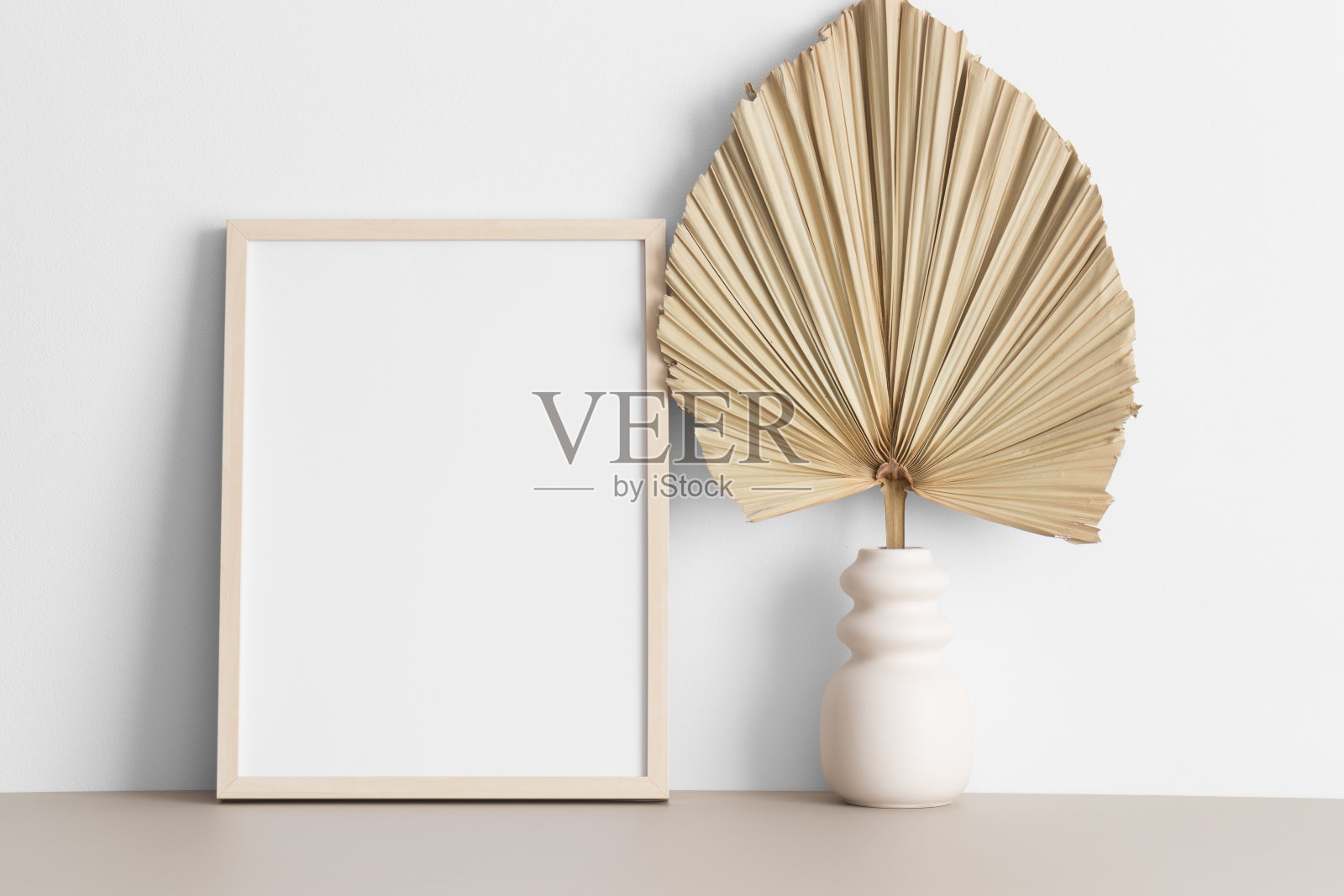 米色桌子上的木制框架模型和棕榈叶装饰。照片摄影图片