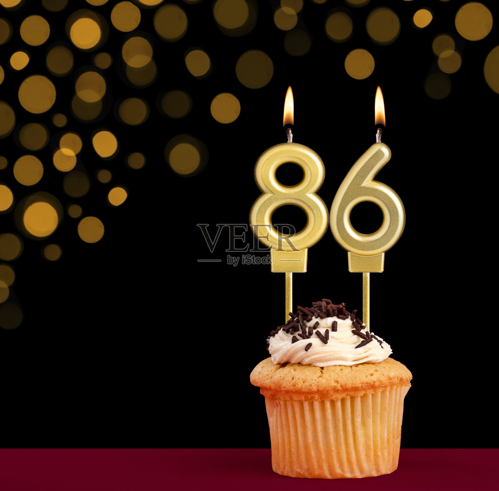 86号生日蜡烛-纸杯蛋糕黑色背景与失焦灯照片摄影图片