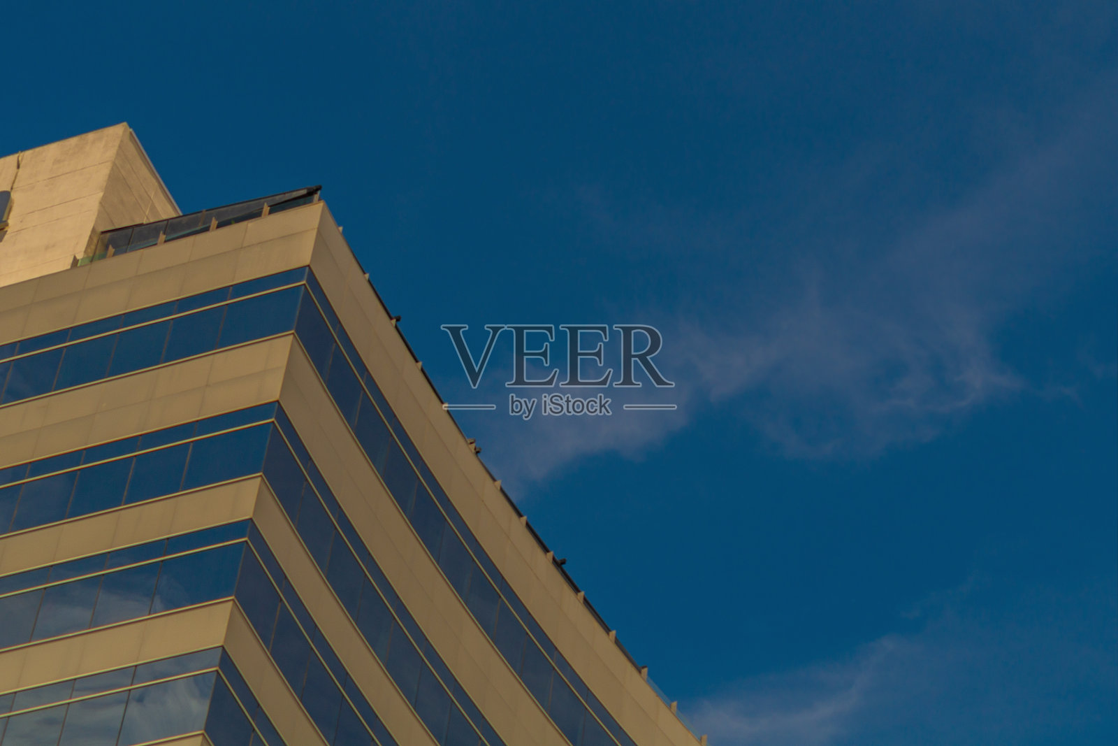 建筑的外部是半圆形的,墙壁上有淡黄色的色调,蓝色的全景窗映衬着湛蓝的天空。视野受阻的地平线照片摄影图片