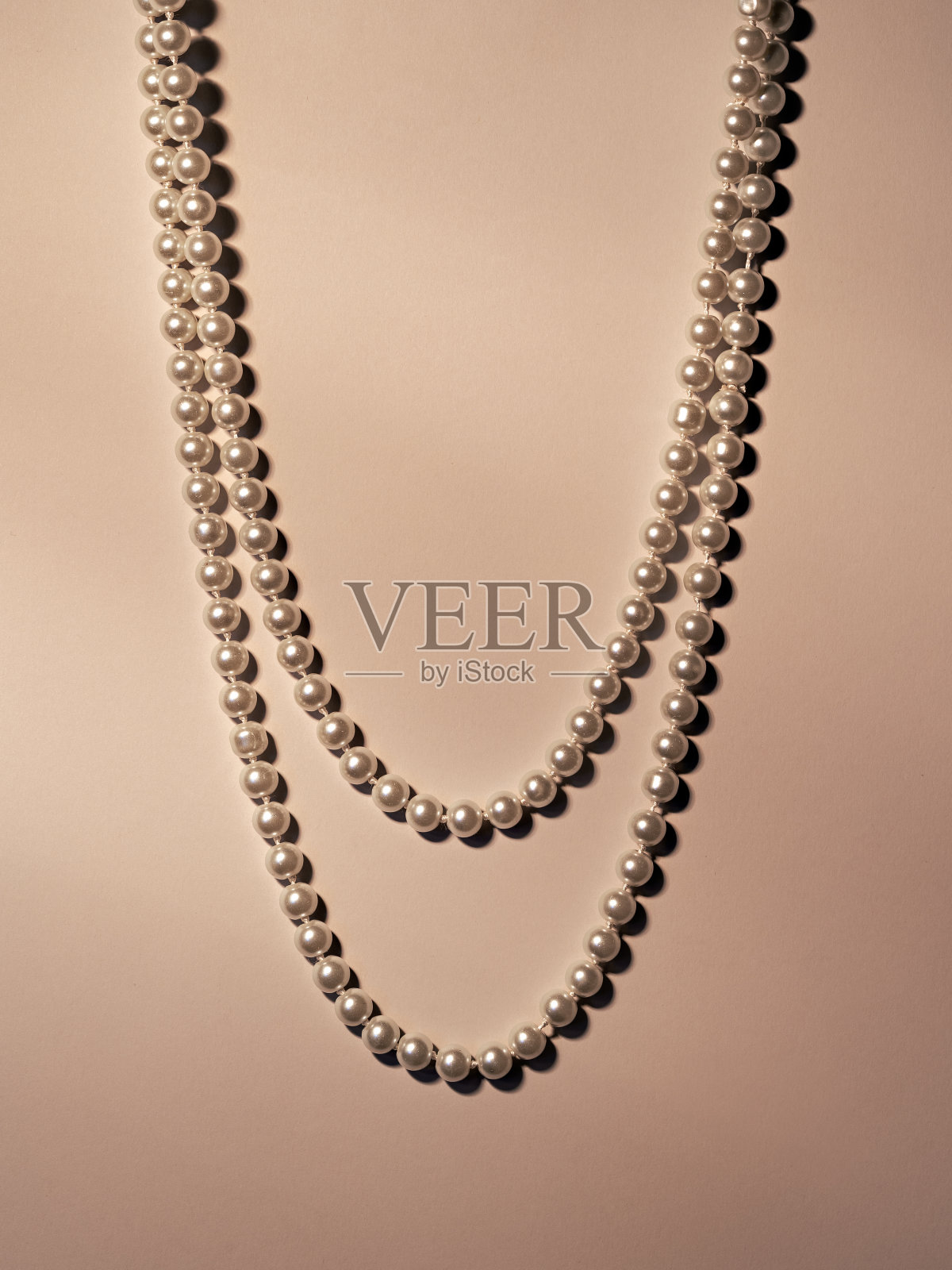 珍珠项链在米色的背景与美丽的光照片摄影图片