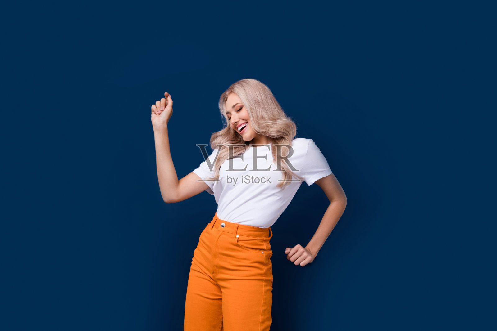 照片积极乐观的女孩穿着白色衣服跳舞的生日聚会孤立在深蓝色的背景照片摄影图片