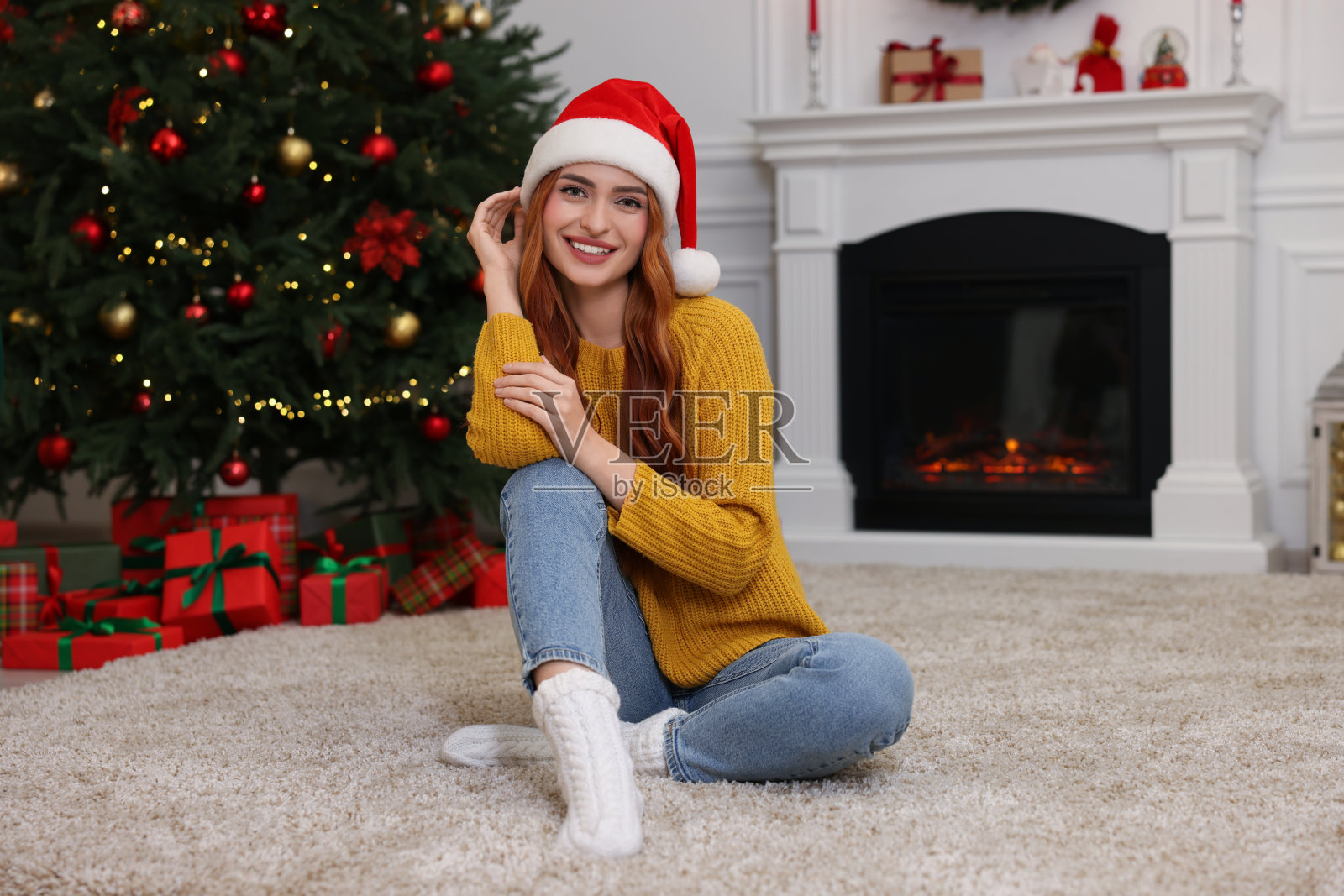 美丽的年轻女子戴着圣诞老人的帽子,在为圣诞节装饰的房间里照片摄影图片