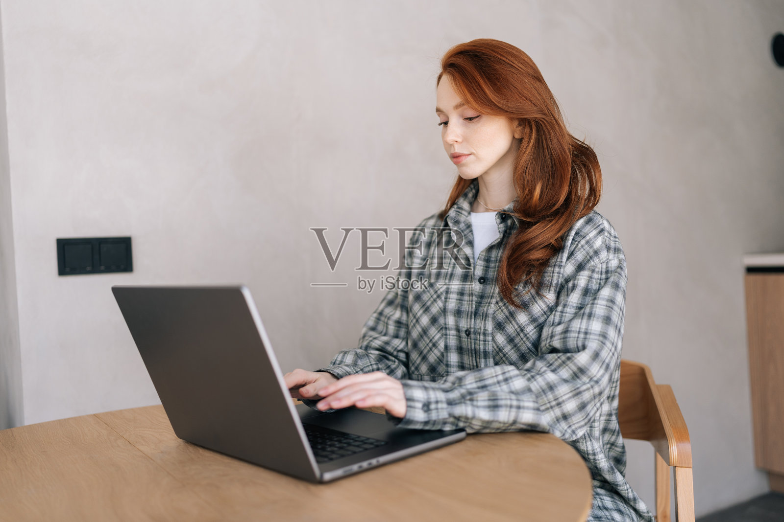 漂亮的年轻女子坐在办公桌前,在家庭办公室的电脑上工作。可爱迷人的女士看着笔记本电脑屏幕,购物,在社交网络上聊天照片摄影图片