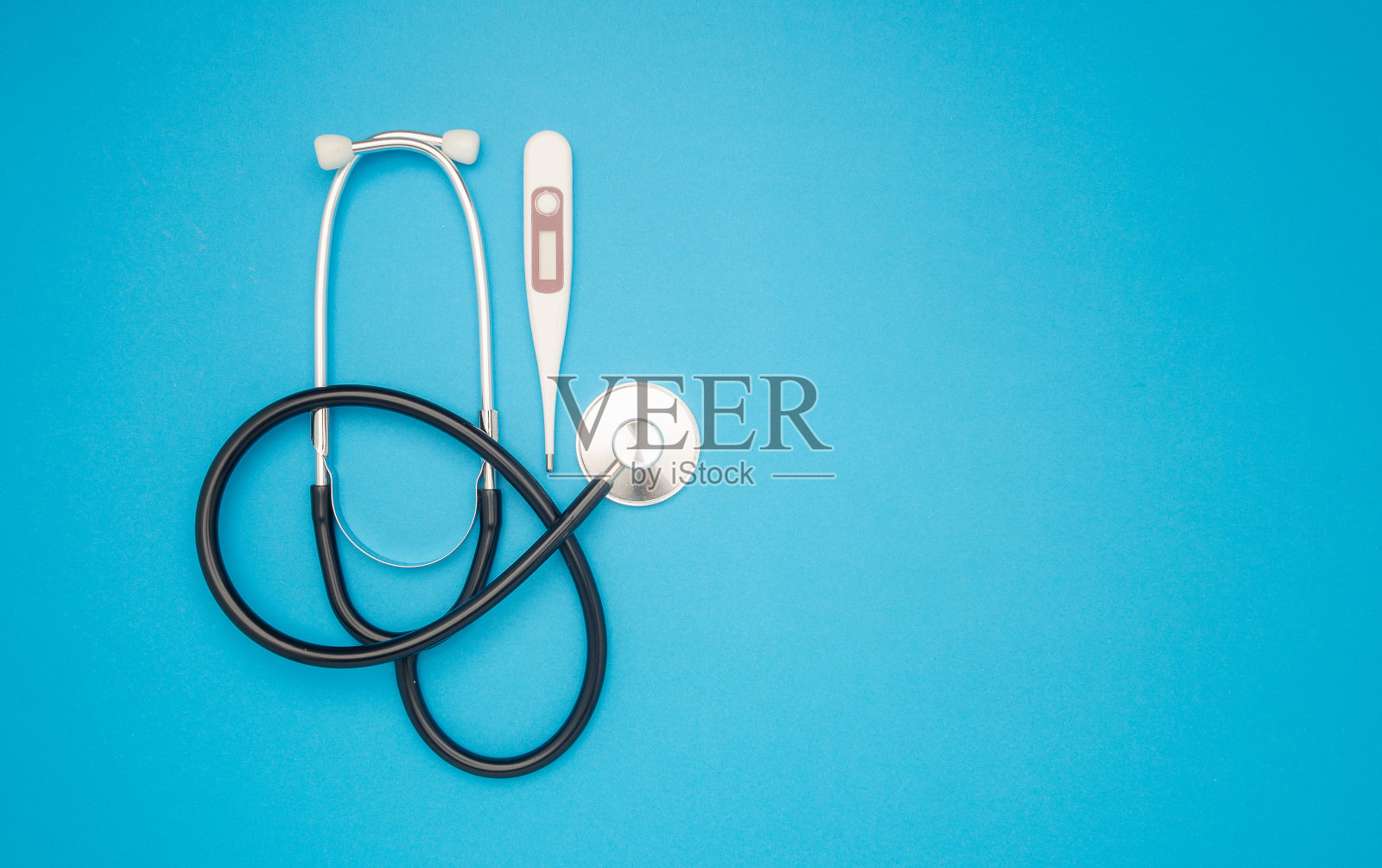 蓝色背景上的听诊器和医用温度计。照片摄影图片