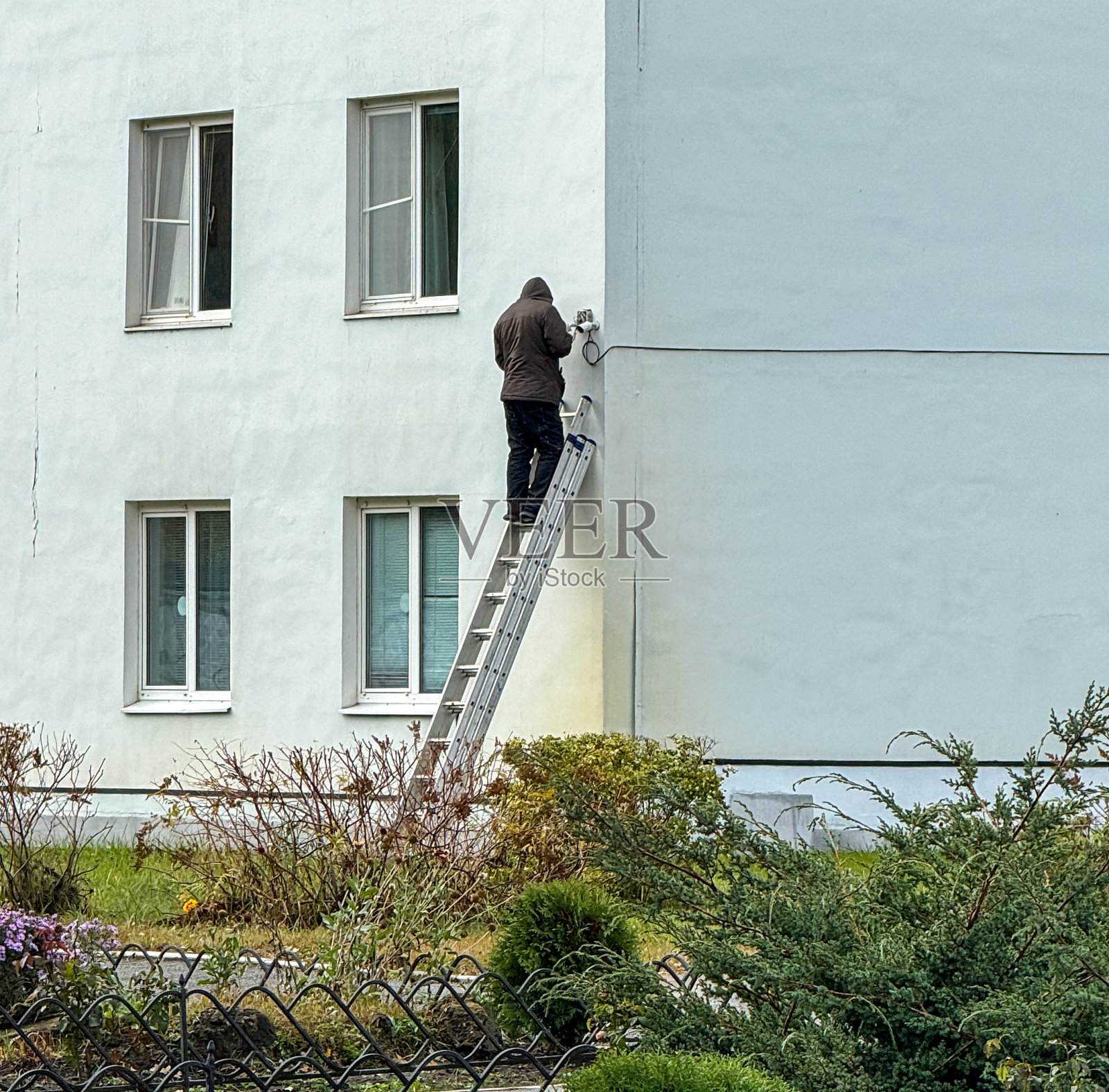 楼梯上的一个人在房子的墙上安装了闭路电视摄像头照片摄影图片