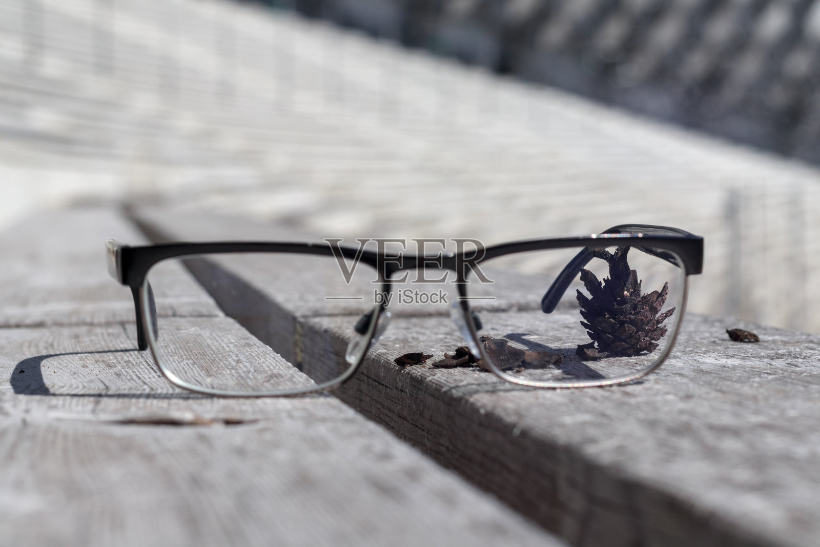 木凳上放着眼镜,背景是眼镜后面的松果照片摄影图片