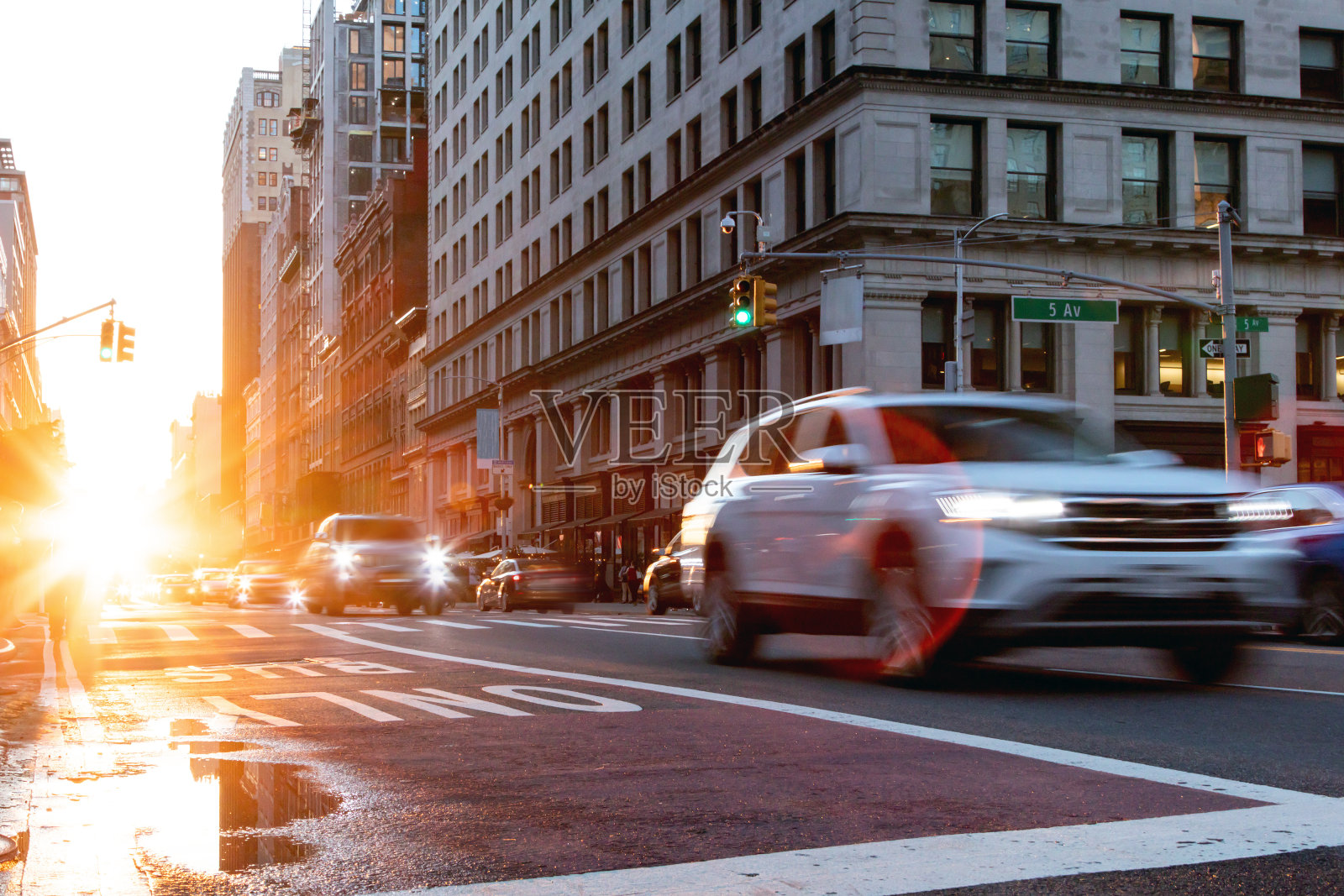 在纽约曼哈顿中城第23街行驶的汽车前灯模糊,背景是阳光照片摄影图片