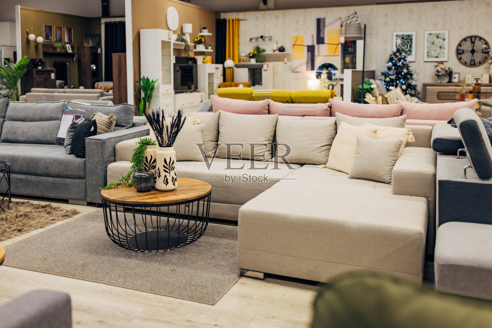 百货商店里展示的米色沙发床,有装饰枕头,床前铺着地毯,还有一张茶几照片摄影图片