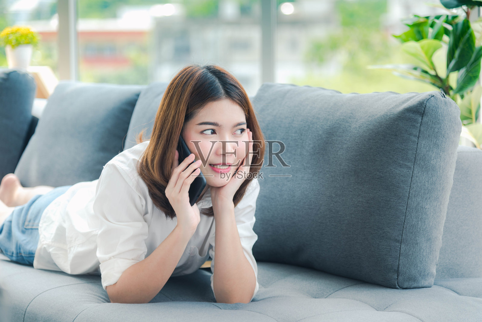 微笑的亚洲女人拿着电子商务的智能手机,购物在线网站阅读在线文章,博客,视频博客。年轻女子手握手机科技生活方式。使用智能手机的女人。照片摄影图片