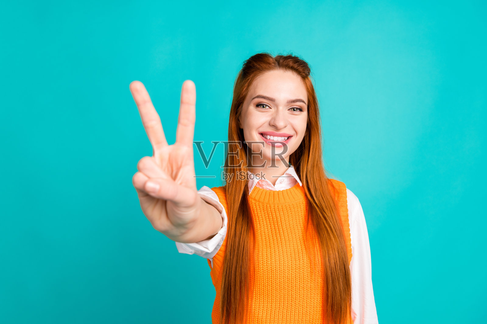 漂亮的年轻女孩的照片肖像v字手势穿着时髦的橙色针织服装孤立的青色背景照片摄影图片