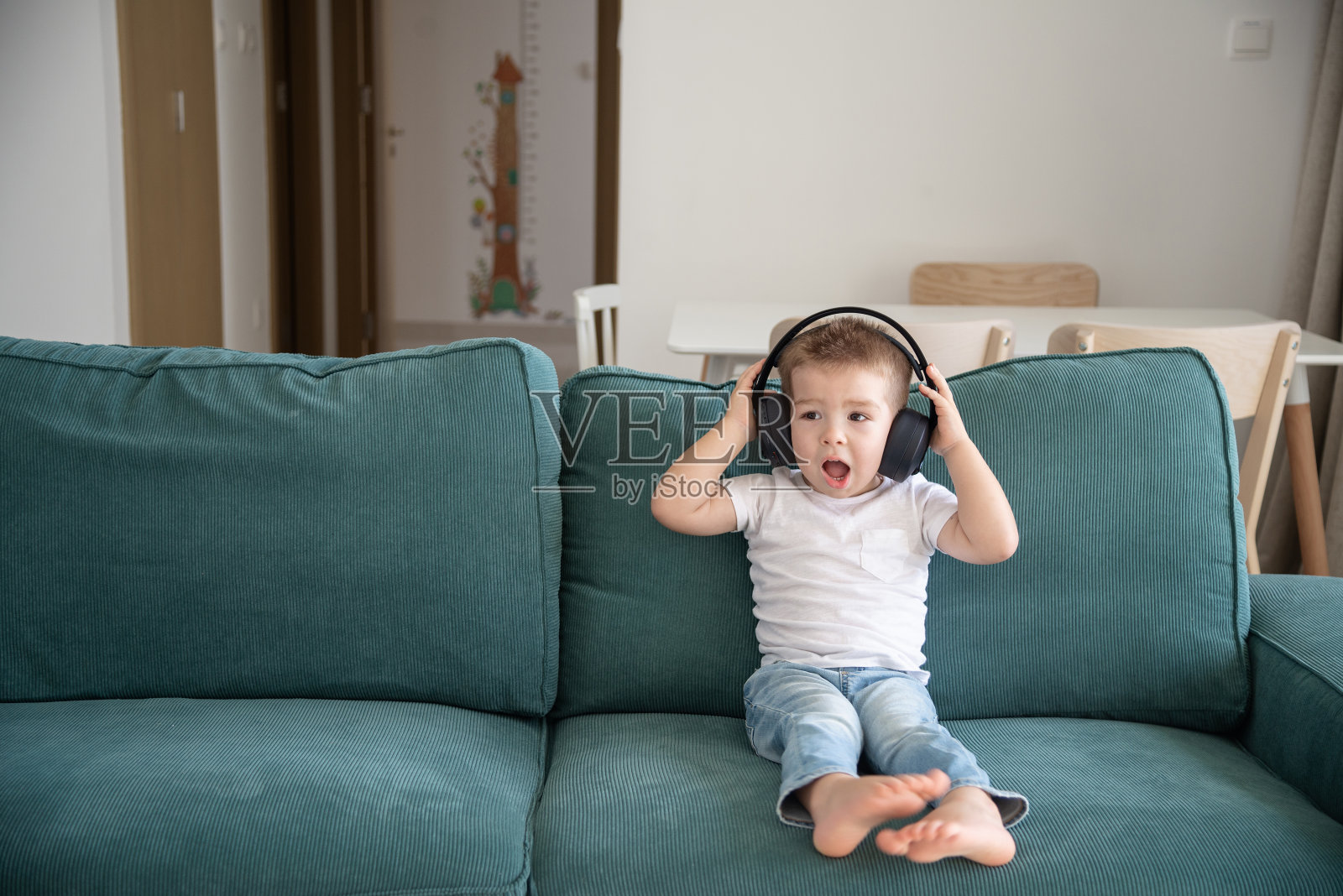 在客厅里戴着耳机听音乐的可爱小男孩照片摄影图片