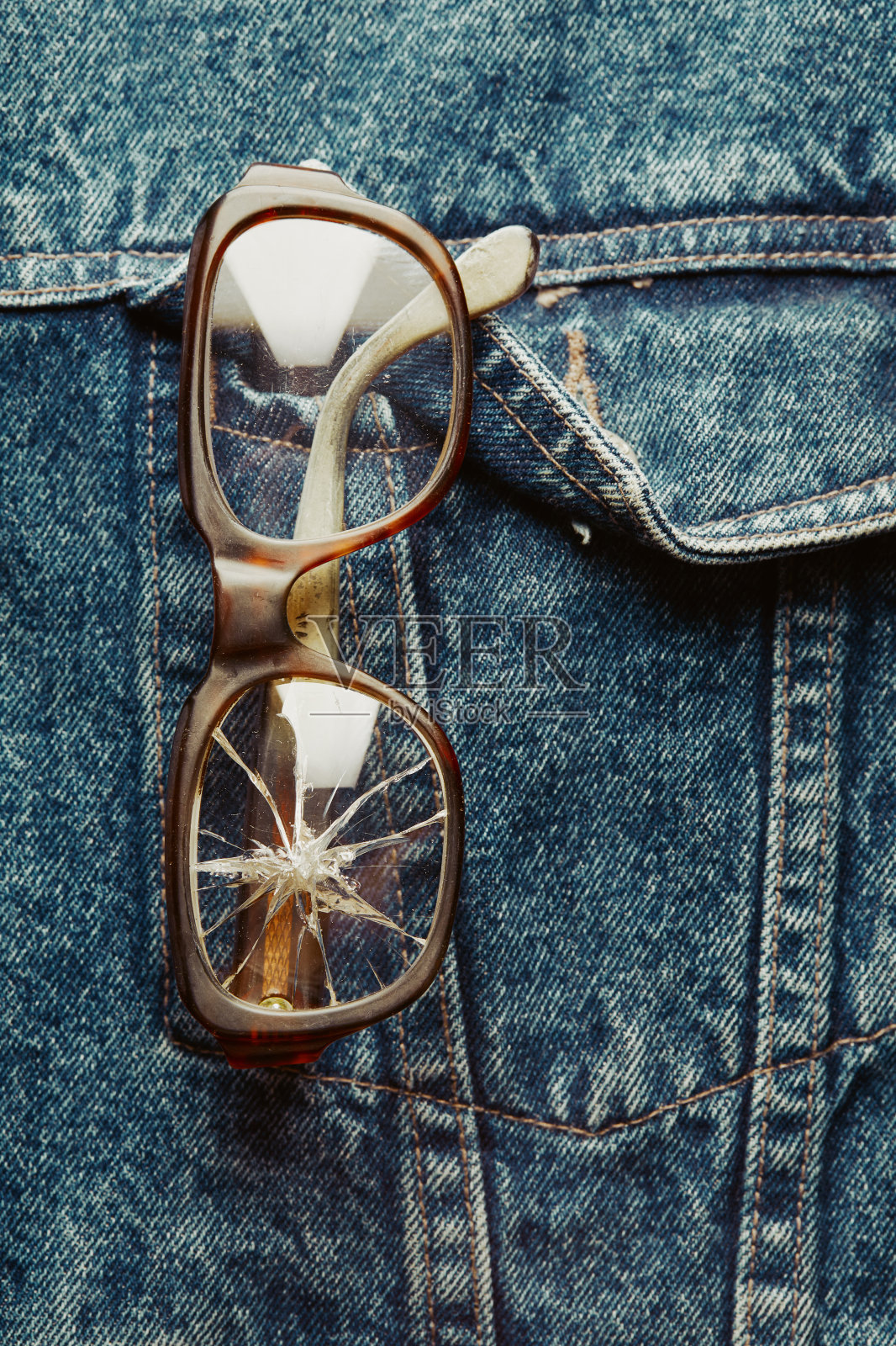牛仔夹克口袋上的破损眼镜照片摄影图片