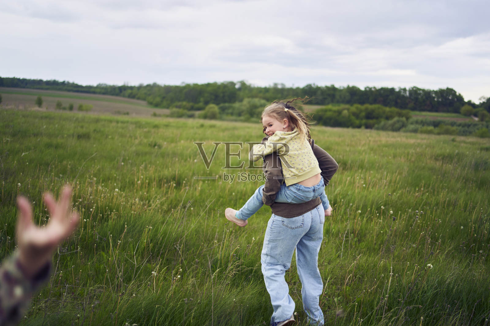 一位母亲把女儿们抱在背上,玩着骑马的游戏,亲吻和拥抱照片摄影图片