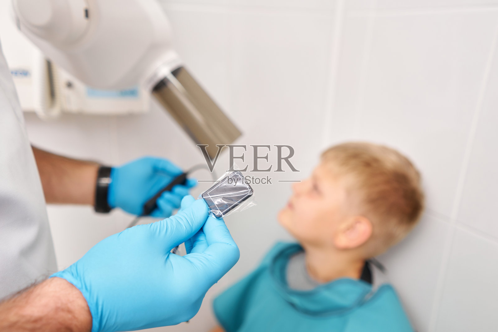 传感器是单独包装的。特写镜头。在儿童牙科诊所,放射技师用数字x光机给一个男孩做牙齿x光片。照片摄影图片