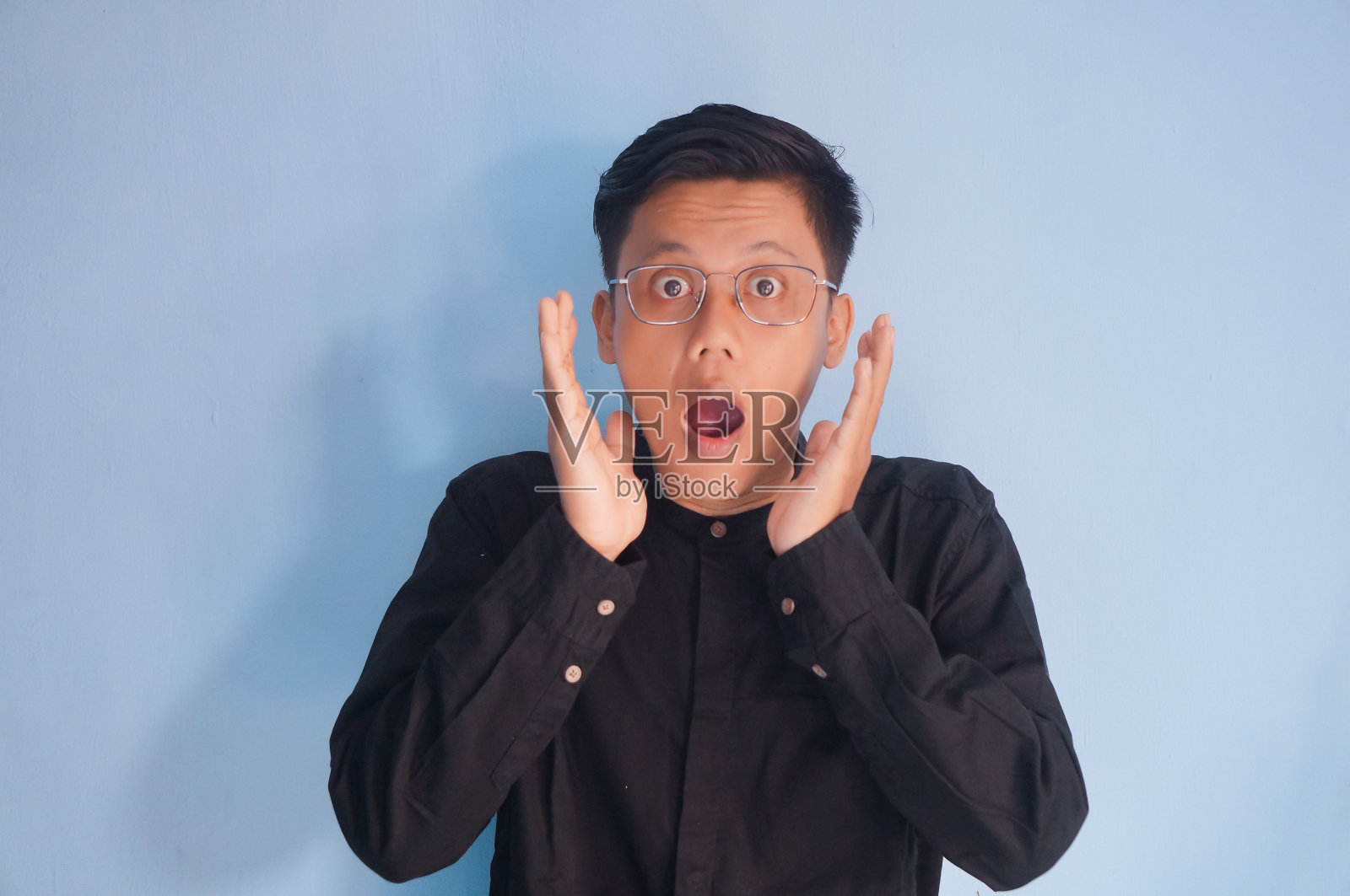 穿着黑衬衫的年轻亚洲男子脸上惊讶的表情照片摄影图片