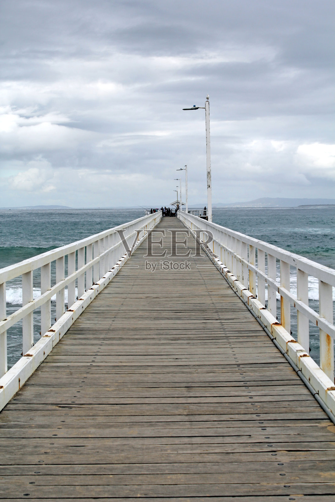 在澳大利亚维多利亚州朗斯代尔角阴云密布的天空下,长长的木制码头码头延伸到大海照片摄影图片