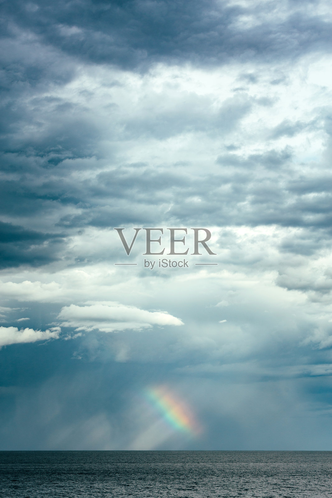 暴风雨云的海景和远处地平线上的彩虹照片摄影图片