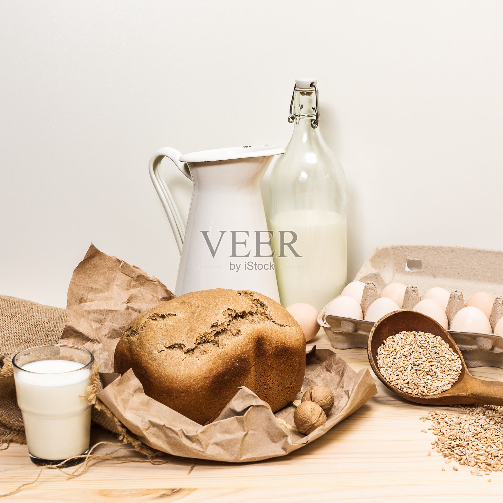 组成面包,一瓶牛奶,一包鸡蛋,一杯牛奶,散落的谷物,一个罐子放在一个轻木桌上照片摄影图片